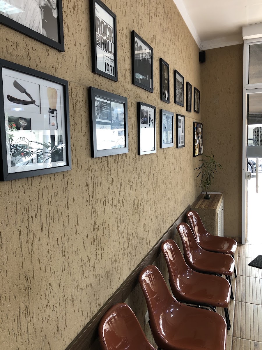 Parede do salão com quadros em preto e branco e cadeiras de espera