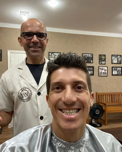 Edi ao lado de um cliente sorridente, depois do corte